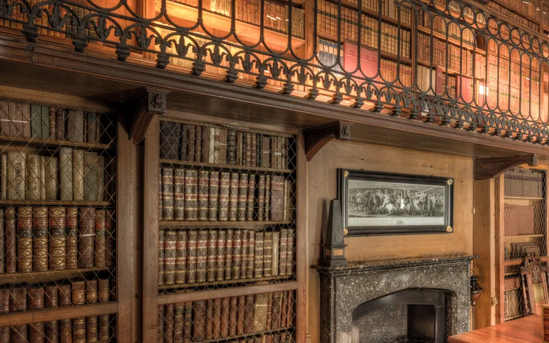 Holzvertäfelte Bibliothek mit Galerie, vergitterten Bücherschränken und Kamin